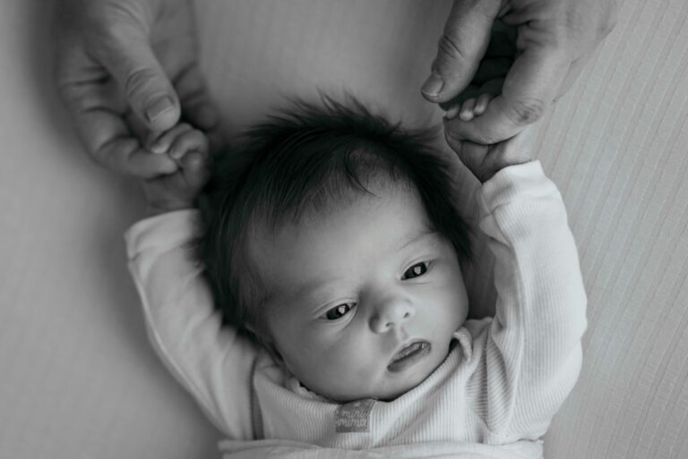 Close-up of a newborn baby holding hands with a parent, showcasing love and bonding.