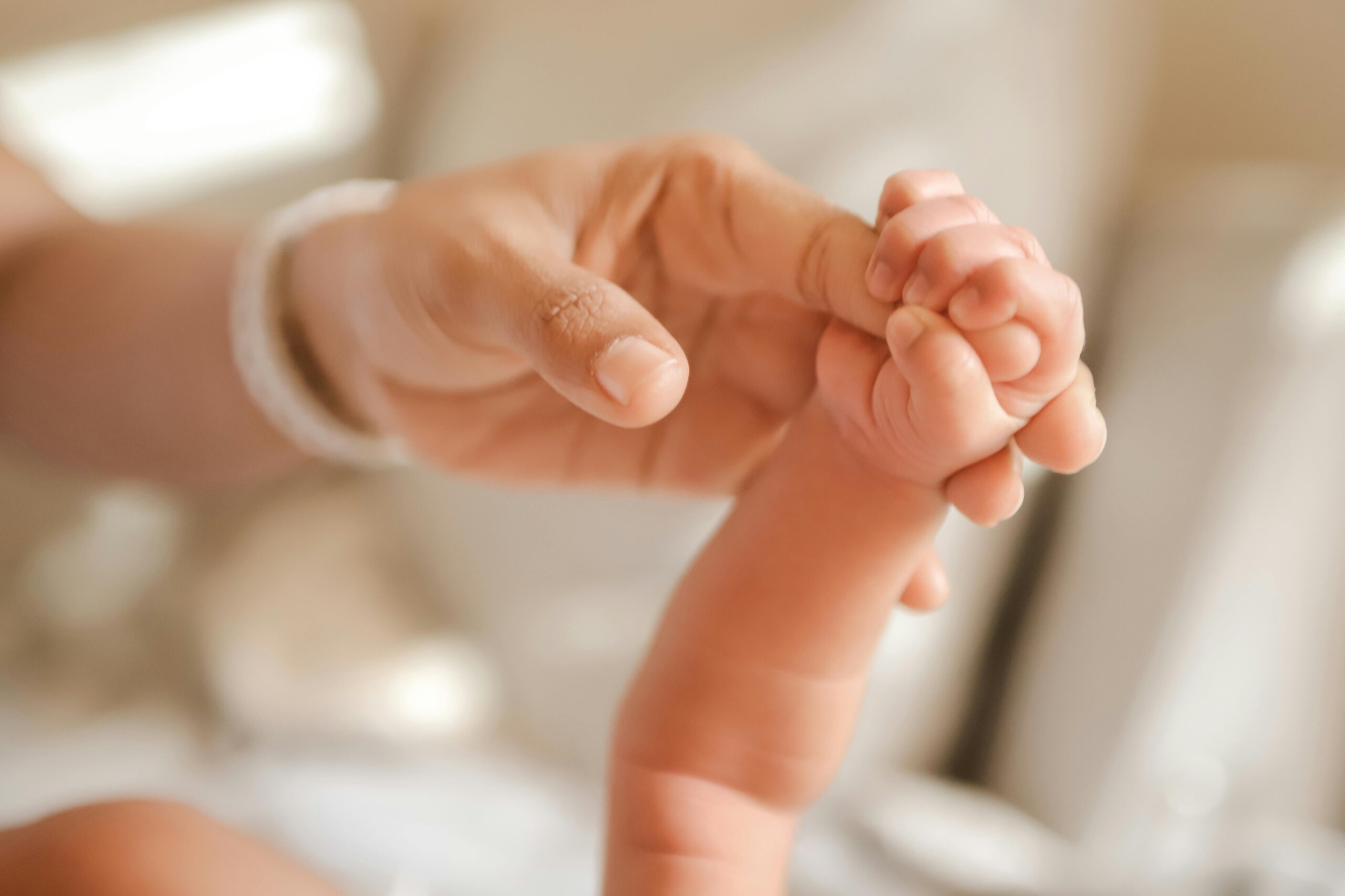 Heartwarming image of a newborn holding an adult's finger, symbolizing connection and care.